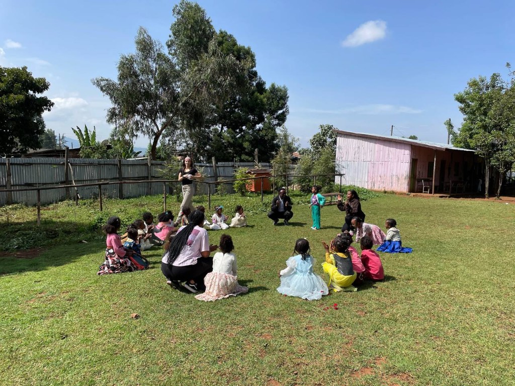 Mission trip team gathered in a circle with children during community programming