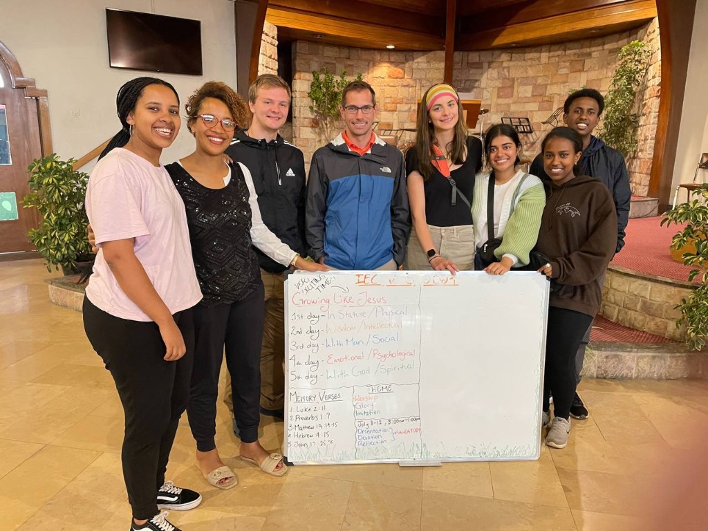 Mission trip volunteers standing with a VBS planning board at a local church