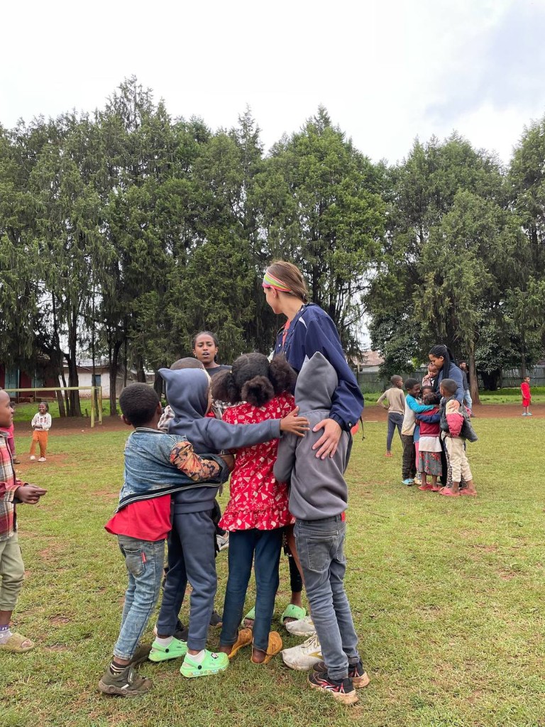 Mission trip volunteer embraced by children during field ministry in Ethiopia